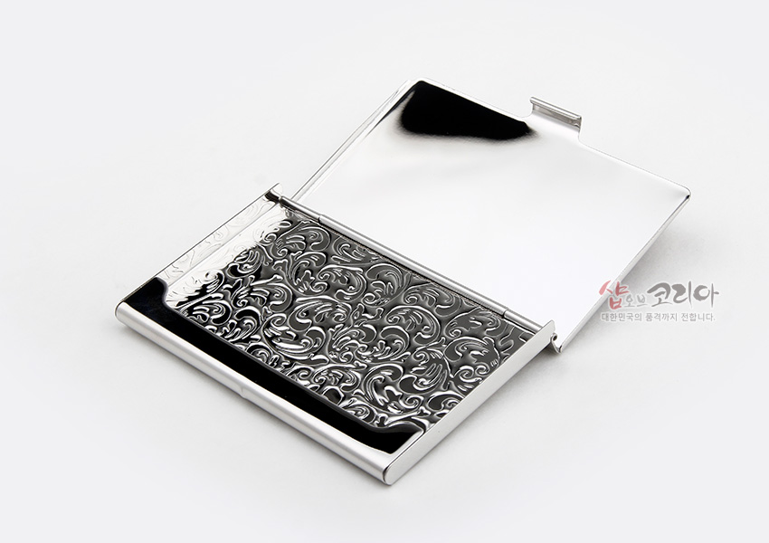 [텍스트: 샵오브코리아 대한민국의 품격까지 전합니다.] 은은한 광택의 금속 재질 위에 섬세한 음각 시조문과 식물 문양이 장식된 실버톤 명함케이스 디자인
