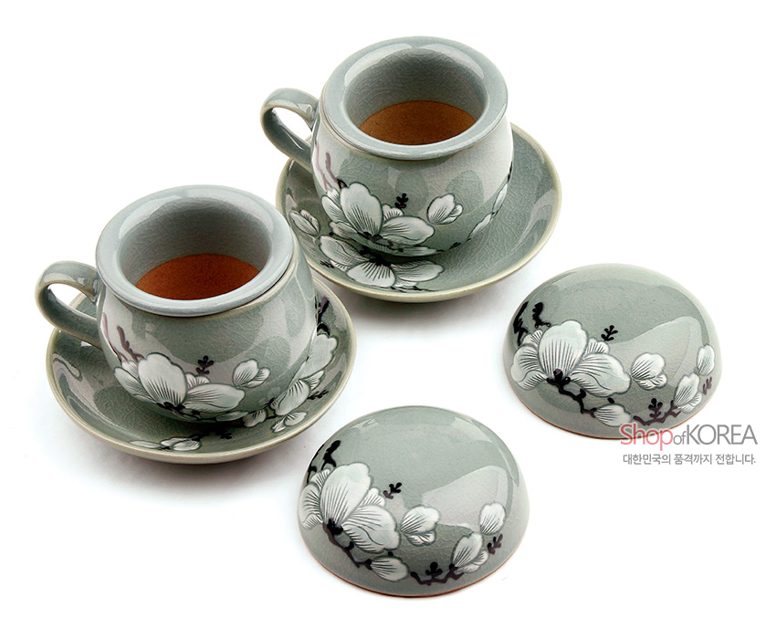 [텍스트: shopofKOREA 대한민국의 품격까지 전합니다.] 옅은 청자 유약 위에 상감기법으로 표현한 백색 목련 화조문이 둘러진 2인용 도자기 찻잔과 뚜껑, 받침 세트 구성