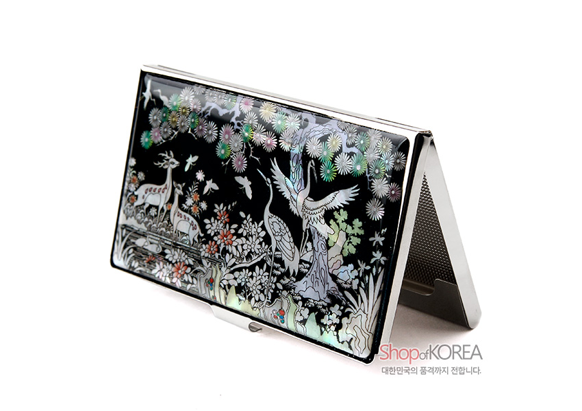 [텍스트: Shop of KOREA 대한민국의 품격까지 전합니다.] 흑색 바탕 위 자개 상감 기법으로 학과 사슴, 소나무와 꽃, 구름 문양을 섬세하게 표현한 금속 명함케이스 디자인