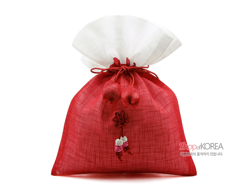 [텍스트: Shop of KOREA 대한민국의 품격까지 전합니다.] 붉은 모시 천과 흰색 모시 상단이 배색된 복주머니, 앞면 전통 매듭과 복숭아 모양 자수 장식 특징의 공예품