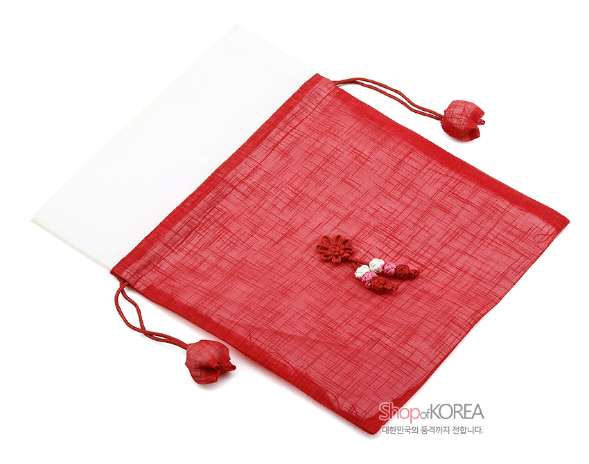 [텍스트: Shop of KOREA, 대한민국의 품격까지 전합니다.] 붉은 모시와 흰색 모시 배색으로 된 전통 주머니, 중앙 꽃매듭과 복숭아 모양 매듭 장식이 더해진 매듭 공예 주머니형 디자인