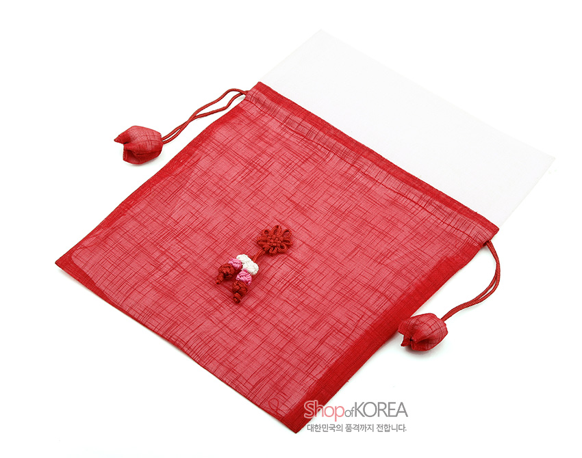 [텍스트: ShopofKOREA 대한민국의 품격까지 전합니다.] 붉은 모시 천과 흰색 배색으로 제작된 전통 복주머니, 중앙 꽃 매듭과 오방색 술 장식, 양 끝 연꽃 모양 매듭 장식이 돋보이는 디자인
