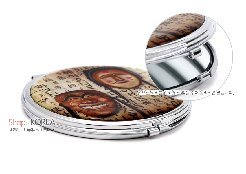 [텍스트: Shop of KOREA, 대한민국의 품격까지 전합니다, 손으로 고리를 잡고 위로 힘을 주어 올리시면 열립니다.] 금속 프레임에 갈색 한지 질감 배경과 하회탈 문양을 인쇄한 원형 양면 손거울 디자인