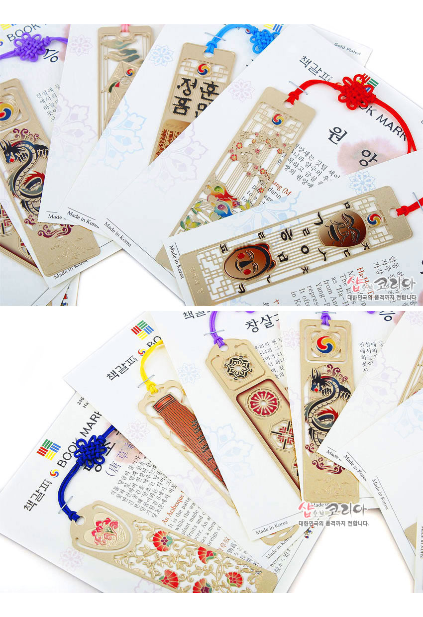 [텍스트: BOOK MARK, Made in Korea, 책갈피, 창살문, 금장, 샵오브코리아] 금속 위 금장 처리된 직사각 책갈피에 태극 문양, 훈민정음 글자, 창살문과 기악·탈·용·매화 등 전통 문양, 색색 전통 매듭 끈 장식 이미지설명