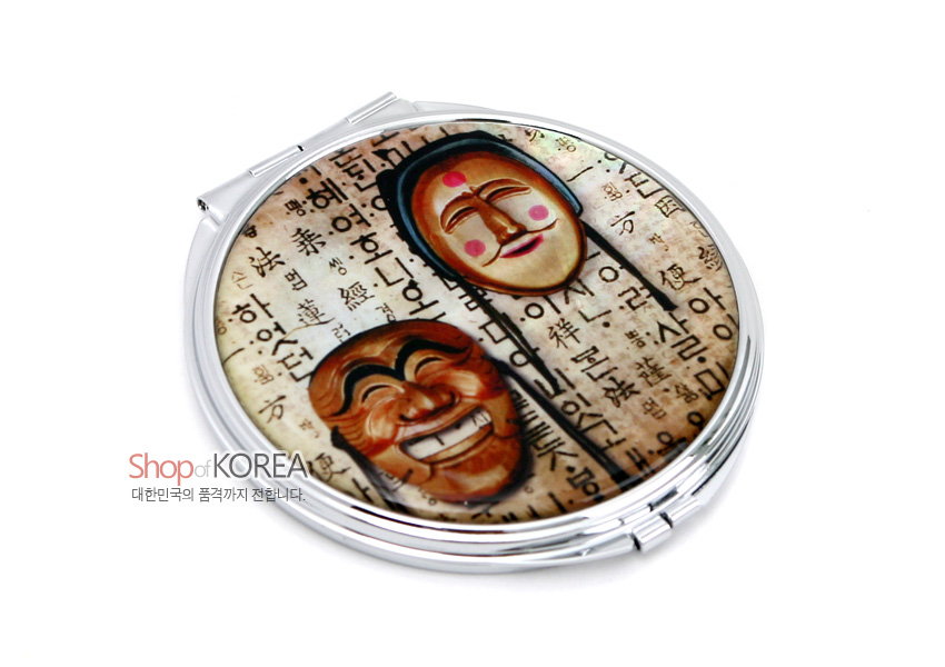 [텍스트: Shop of KOREA, 대한민국의 품격까지 전합니다.] 금속 원형 프레임 위에 갈색·살구색 하회탈 문양과 한글 배경을 인쇄한 광택 있는 표면의 휴대용 손거울 디자인