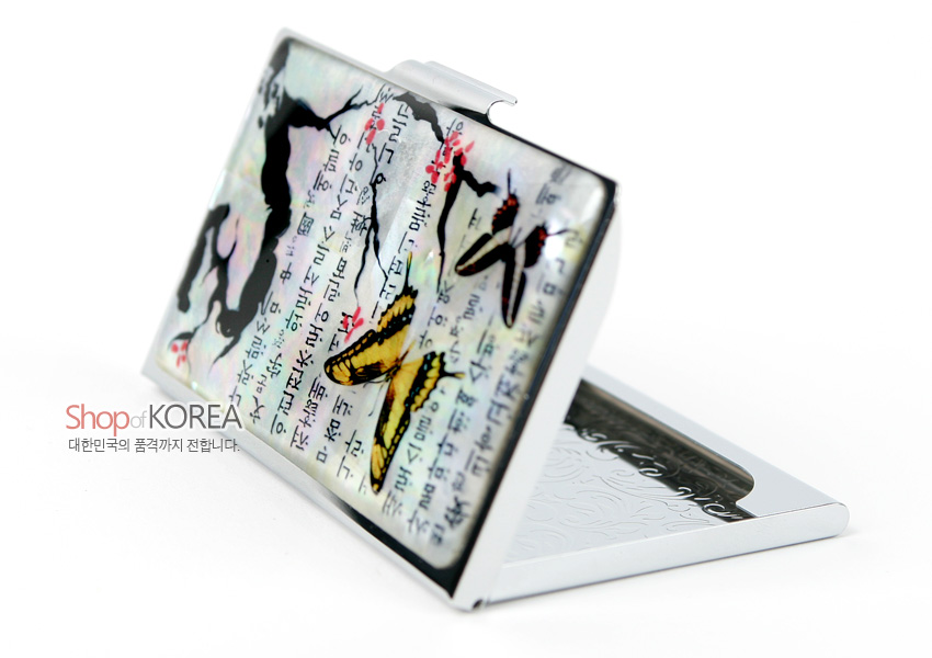 [텍스트: Shop of KOREA 대한민국의 품격까지 전합니다.] 자개 광택 위 매화 가지와 노랑·갈색 나비, 세로형 한글 글귀가 어우러진 금속 명함케이스 장식 이미지
