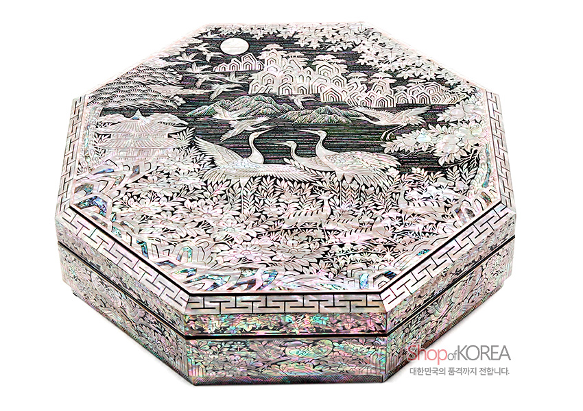 [텍스트: Shop of KOREA 대한민국의 품격까지 전합니다.] 팔각 형태 옻칠 바탕 위에 자개 상감 기법으로 학과 사슴, 소나무와 산수 장생도문을 섬세하게 조각한 구절함 이미지 설명