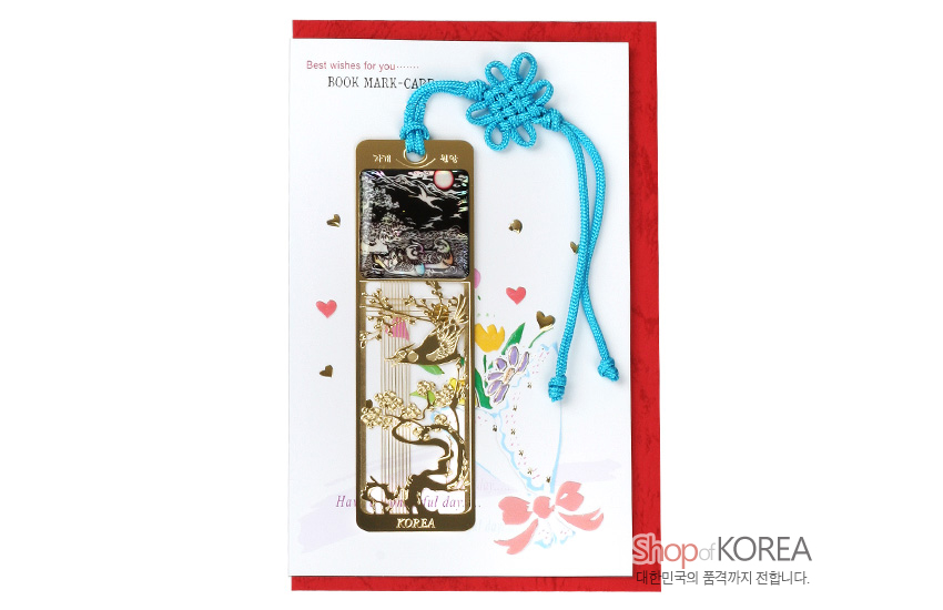 [텍스트: 자개 책갈피, KOREA, BOOK MARK-CARD, Best wishes for you......, shopofKOREA 대한민국의 품격까지 전달합니다.] 금속 재질 위 자개 상감으로 원앙과 꽃, 소나무 문양을 넣고 청색 전통 매듭 끈을 더한 금장 책갈피 이미지 설명