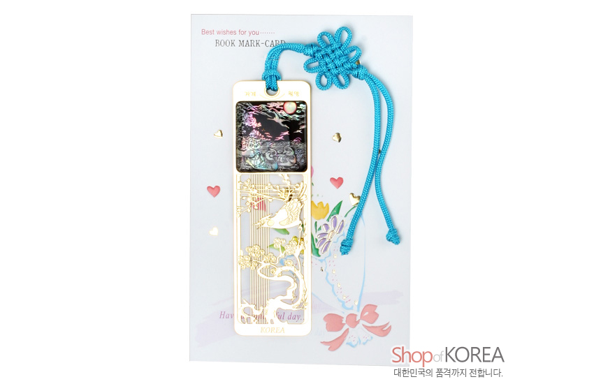 [텍스트: Best wishes for you… BOOK MARK-CARD 자개 책갈피 Have a good day. KOREA Shop of KOREA 대한민국의 품격까지 전합니다.] 금속 재질 금장 오픈워크 위에 자개 상감으로 원앙과 소나무, 달과 구름 문양을 담고 청색 전통 매듭 끈으로 장식한 책갈피 이미지 설명