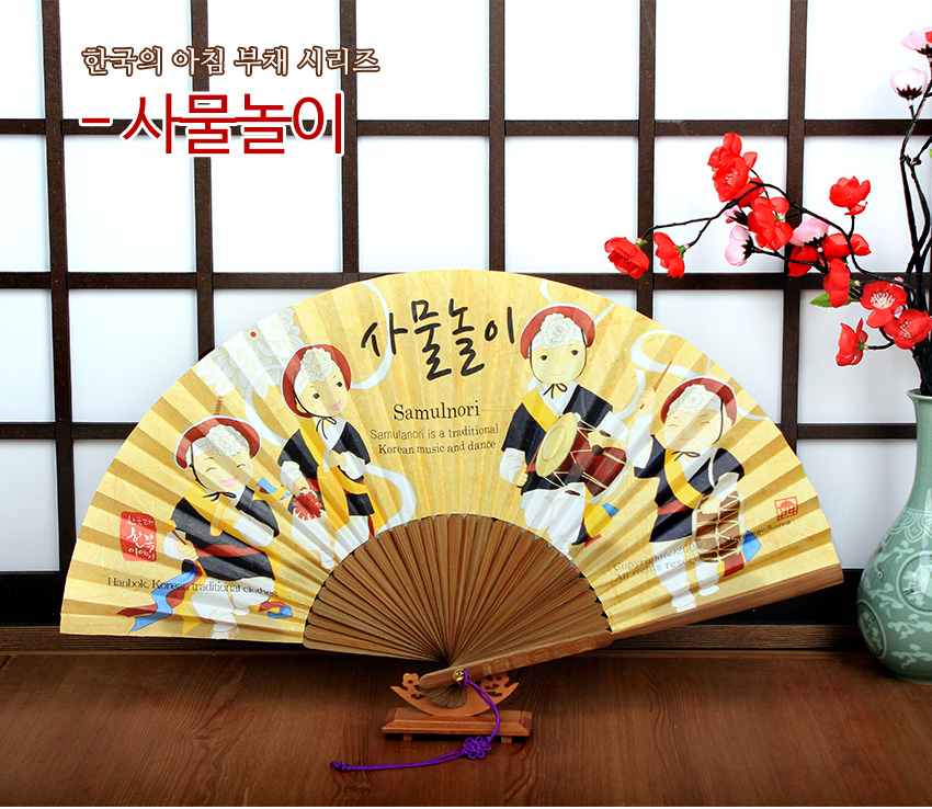 [텍스트: 한국의 아침 부채 시리즈 - 사물놀이 / Samulnori / Samulnori is a traditional Korean music and dance / Hanbok, Korean traditional clothes] 노란 스트라이프 배경 위 사물놀이 일러스트와 나무 살대로 구성된 전통 한지 부채 이미지 설명