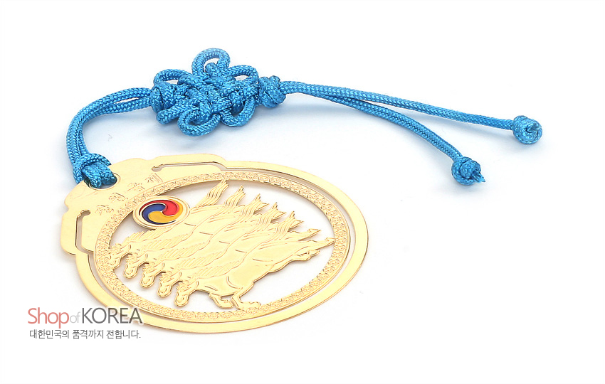 [텍스트: Shop of KOREA, 대한민국의 품격까지 전합니다.] 금속 재질에 24K 금장 처리된 원형 마패 문양, 다섯 말과 태극 문양 장식, 하늘색 전통 매듭 끈으로 마무리된 디자인
