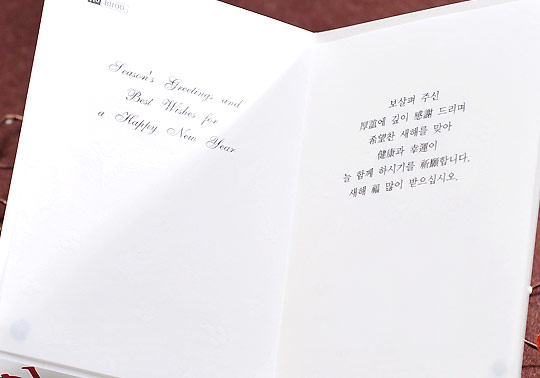 [텍스트: Season's Greetings and Best Wishes for a Happy New Year / 보살핌 주신 어쩌고… 새해 복 많이 받으십시오.] 흰색 종이 재질, 영문 필기체와 한글 인쇄 문구가 나뉘어 배치된 양면 펼침 연하장 내부 디자인