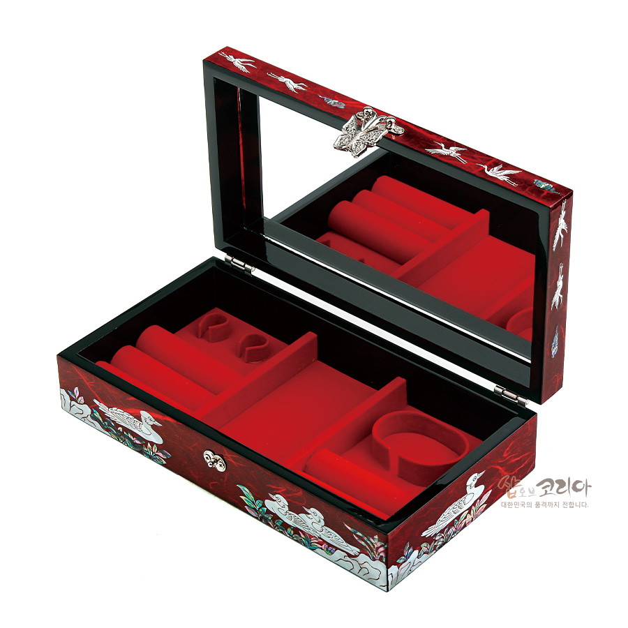 [텍스트: 샵오브코리아 대한민국의 품격까지 전합니다.] 붉은 옻칠 바탕 위 자개 상감 학·소나무·구름 문양과 내부 붉은 벨벳 칸막이, 뚜껑 거울과 금속 장식을 갖춘 직사각 보석함 이미지 설명