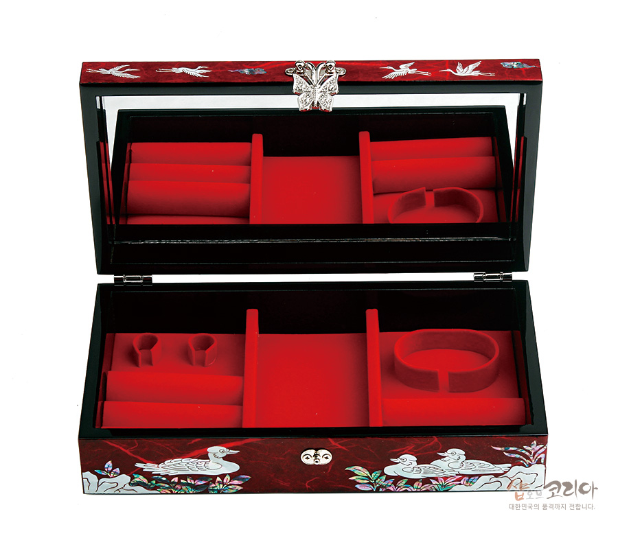 [텍스트: 샵코리아 대한민국의 품격까지 전합니다.] 붉은 옻칠 바탕 위 학과 꽃 문양을 자개 상감으로 장식하고, 내부는 붉은 벨벳 칸막이로 구성된 직사각형 보석함 이미지 설명