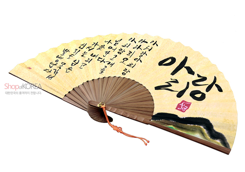 [텍스트: 아리랑 아리랑 아라리요 아리랑 고개로 넘어간다 나를 버리고 가시는 님은 십리도 못 가서 발병난다] 한지 위 먹색 아리랑 가사와 산수화, 연한 황토색 배경과 나무 살대, 전통 매듭 장식의 합죽선 디자인