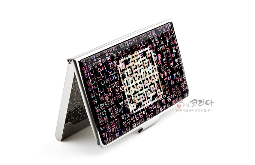 [텍스트: 샵오브코리아 대한민국의 품격까지 전합니다.] 흑색 바탕 위에 다채로운 자개 상감 한글 시조문과 중앙 QR코드형 기하문을 금속 케이스에 조화시킨 명함집 디자인