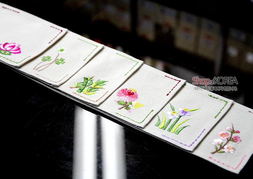 [텍스트: ShopofKOREA 대한민국의품격까지 전합니다] 광목 소재 위에 대나무와 다양한 꽃 자수를 놓고 컬러 스티치 라인으로 마감한 전통 문양 패턴 이미지