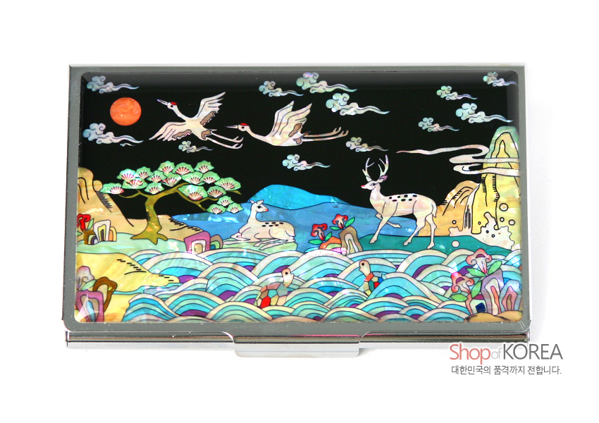[텍스트: Shop of KOREA 대한민국의 품격까지 전합니다.] 흑색 바탕에 자개 상감 기법으로 십장생의 해, 학, 사슴, 거북, 파도, 구름, 소나무를 다채로운 색감으로 표현한 금속 명함집 디자인
