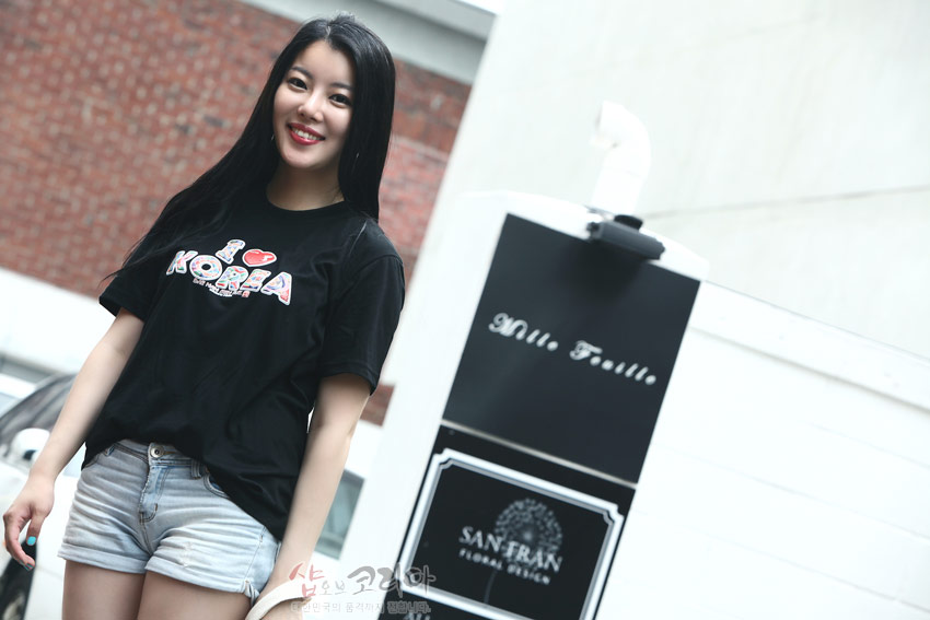 [텍스트: I ♥ KOREA] 흑색 면 소재 위에 컬러풀한 전통무늬를 채운 영문 레터링을 3D 입체발포 기법으로 표현한 반소매 티셔츠 모습