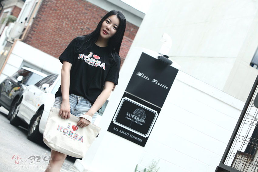 [텍스트: I ♥ KOREA] 흑색 면 티셔츠 위 컬러풀한 전통무늬 3D 입체발포 레터링 장식과 크림색 에코백에 동일한 문양으로 연출된 캐주얼 코디 이미지