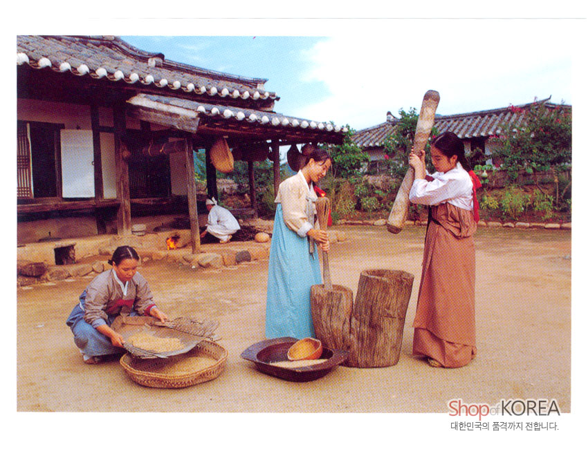 [텍스트: Shop of KOREA / 대한민국의 품격까지 전합니다.] 한옥 마당에서 비단 한복을 입은 여인들이 절구질과 키질로 곡식을 가공하는 전통 농경 풍경 이미지