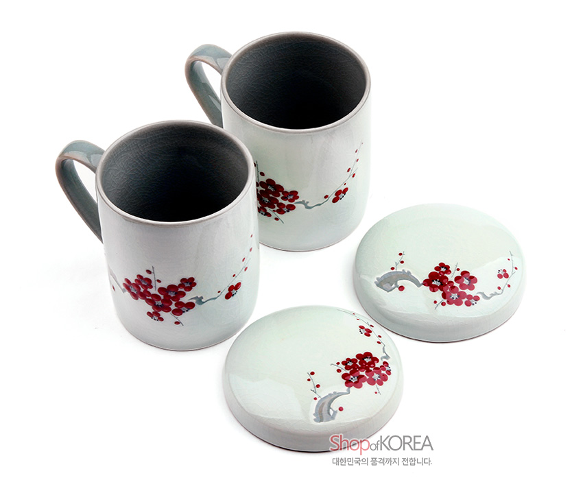 [텍스트: ShopofKOREA 대한민국의 품격까지 전합니다.] 옅은 청자색 바탕 위 붉은 매화 문양과 청록색 손잡이가 조화를 이루는 뚜껑 포함 도자기 머그 2인 세트 이미지 설명