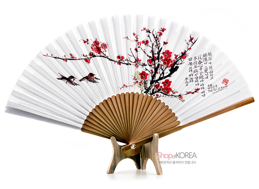 [텍스트: The fan of Korea] 흰 종이 위 붉은 매화와 새가 수묵채색으로 그려진 합죽선, 대나무 살대와 한글 서예가 조화를 이루는 전통 부채 디자인