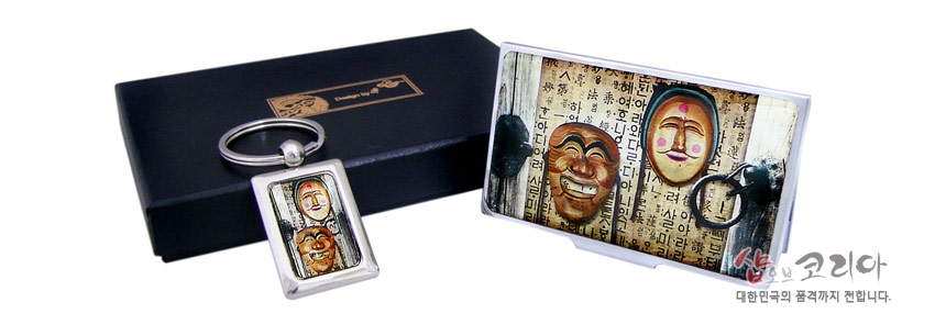 [텍스트: 샵오브코리아, 대한민국의 품격까지 전합니다.] 금속 재질 명함집과 열쇠고리에 하회탈 2종과 한글 서체를 컬러 인쇄한 직사각 패널 장식 구성