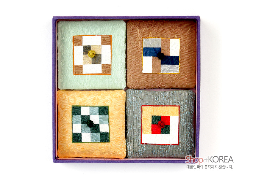 [텍스트: Shop of KOREA 대한민국의 품격까지 전합니다.] 옅은색 비단 바탕 위에 사각 조각보 패턴을 이어 붙이고 중앙에 연봉 매듭 장식을 더한 전통 자석 메모홀더 세트 구성