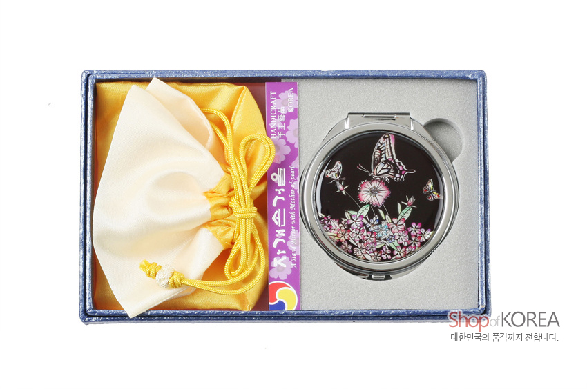 [텍스트: 자개손거울, Shop of KOREA, 대한민국의 품격까지 전합니다.] 검은 바탕 자개 상감 호랑나비와 꽃 문양 금속 손거울과 노랑 매듭 비단 복주머니 구성 선물 상자 모습