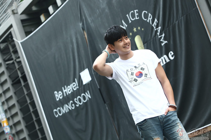 [텍스트: Be Here! COMING SOON / KOREA / Korean / *Korean for foreigners*] 흰색 면 티셔츠 중앙 태극기와 사괘 문양을 입체발포 기법으로 표현한 반소매 티셔츠 착용 모습