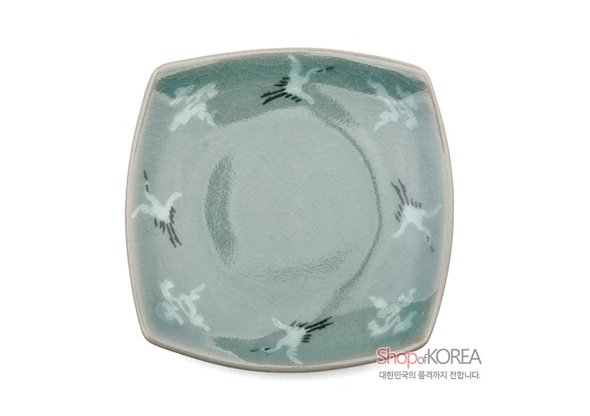 [텍스트: Shop of KOREA 대한민국의 품격까지 전합니다.] 비색청자 재질의 사각 찻잔받침, 은은한 비취색 유약과 균열문, 가장자리에 날아오르는 학 문양 장식 이미지