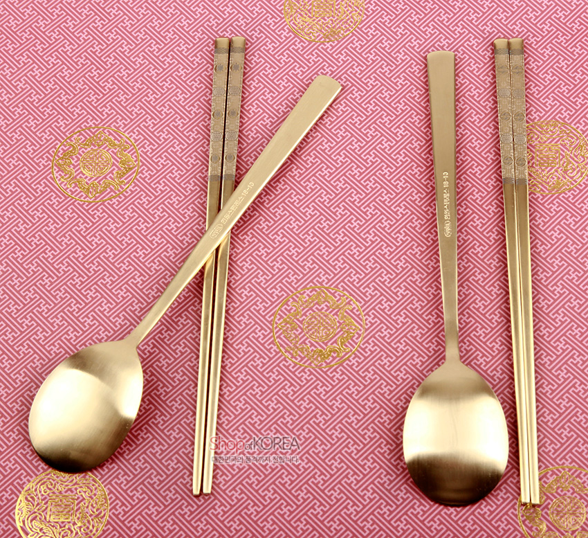 [텍스트: Shop of KOREA] 금빛 티타늄 소재의 숟가락과 젓가락 2인 세트, 손잡이에 정교한 십장생 기하학 문양을 섬세한 음각으로 장식한 디자인