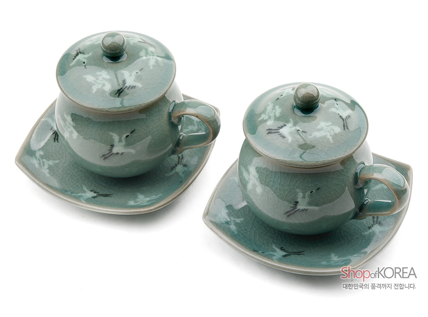 [텍스트: Shop of KOREA 대한민국의 품격까지 전합니다.] 비색청자 재질에 운학 문양 상감, 균열 유약 기법, 연녹색과 회녹색 조화의 뚜껑 찻잔과 사각 받침 2인 세트 이미지 설명