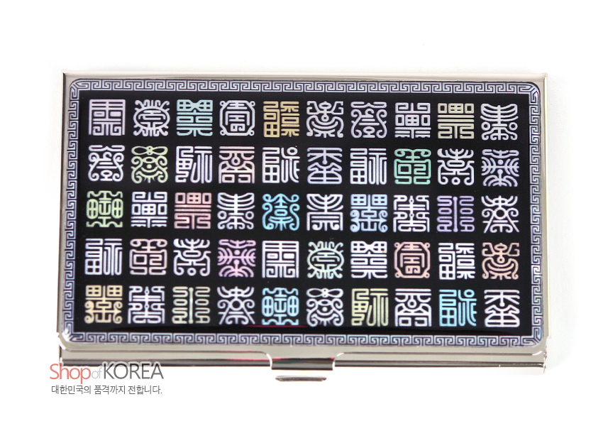 [텍스트: Shop of KOREA 대한민국의 품격까지 전합니다.] 금속 명함집 위 흑색 바탕에 자개 상감 기법으로 다채로운 전서체 한자 문양을 격자 배열하고 가장자리에 그리스 키 문양을 두른 디자인