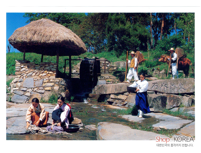 [텍스트: 石水群英, Shop of KOREA, 대한민국의 품격까지 전합니다.] 초가 지붕 수차와 돌담, 물가에서 빨래하는 한복 차림 인물과 소를 모는 농부가 어우러진 전통 농촌 풍경 엽서 이미지