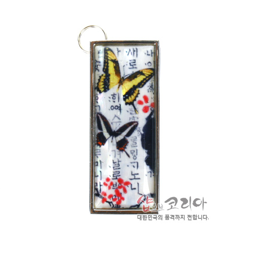 [텍스트: 샵코리아 대한민국의 품격까지 전합니다.] 은은한 한글 서체 배경 위 노랑·검정 나비와 붉은 매화 문양이 채색된 직사각형 금속 테두리 USB 메모리 장식 이미지 설명