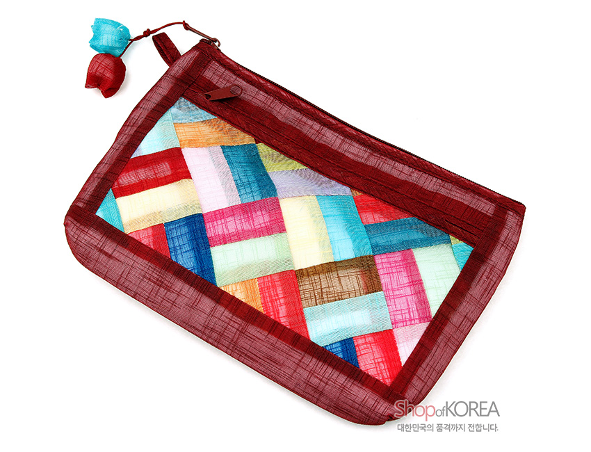 [텍스트: Shop of KOREA 대한민국의 품격까지 전합니다.] 적갈색 모시 테두리에 여러 색 모시 조각을 전통 조각보 기법으로 사선 배치하고, 지퍼 고리에 실크 매듭 장식을 더한 직사각 모시 파우치 이미지설명