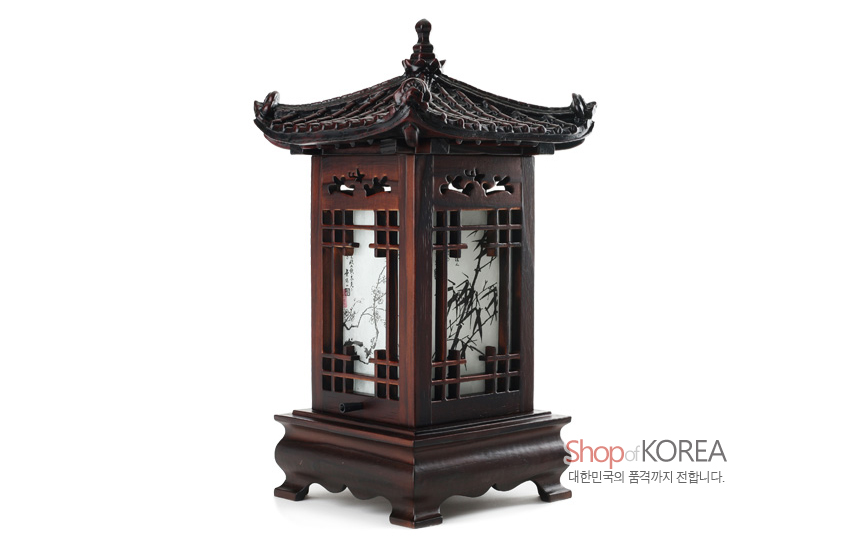 [텍스트: Shop of KOREA 대한민국의 품격까지 전합니다.] 짙은 목재 기와 지붕과 곡선 받침, 창살 무늬 사이 흑백 사군자 한지 조명이 어우러진 전통 좌등 형상
