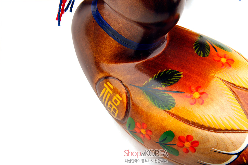[텍스트: 福, Shop of KOREA, 대한민국의 품격까지 전합니다] 나무 재질에 채색 기법으로 표현된 오리 형태 목각, 복자 음각과 붉은·노랑 꽃·초록 잎 문양, 청색 띠와 실 매듭 장식 특징