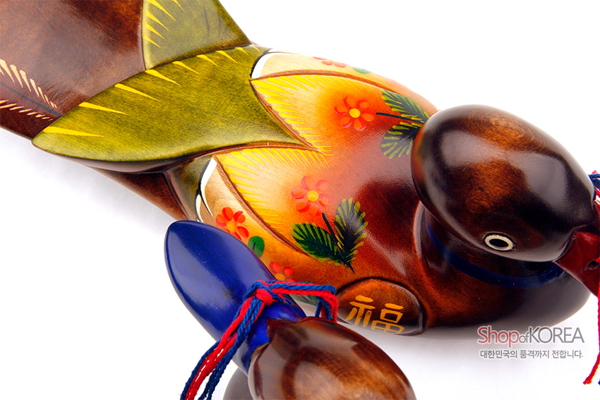 [텍스트: 福, Shop of KOREA, 대한민국의 품격까지 전합니다.] 원목 재질에 채색 기법으로 표현된 꽃과 잎사귀 문양, 황·녹·주황색 그러데이션 날개와 붉은·청색 매듭 끈 장식의 원앙 목각 장식