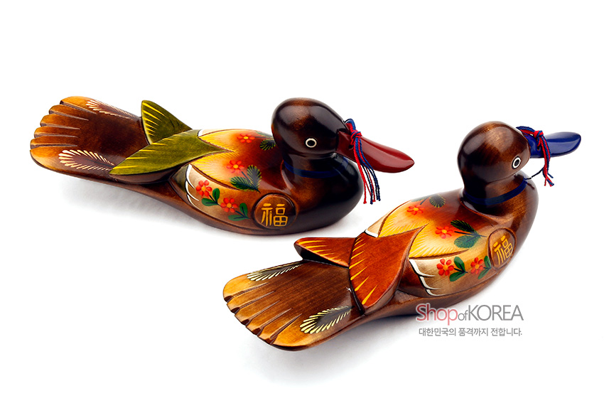 [텍스트: ShopofKOREA 대한민국의 품격까지 전합니다.] 나무 재질에 붉은·노랑·초록 채색으로 꽃과 복(福)자 문양을 더한 원앙 한 쌍 목각 장식, 홍청색 매듭 장식 특징