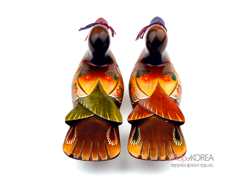 [텍스트: ShopofKOREA 대한민국의 품격까지 전합니다.] 나무 재질에 조각된 원앙 한 쌍, 붉은·노랑·초록 채색의 꽃과 잎사귀 문양, 꼬리 부분 선형 문양과 청·홍색 실매듭 장식