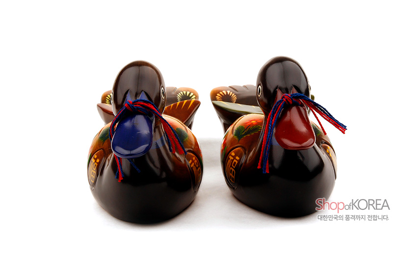 [텍스트: Shop of KOREA 대한민국의 품격까지 전합니다.] 짙은 갈색 나무 재질에 채색 기법으로 꽃과 복(福)자 문양을 더한 원앙 한 쌍, 붉은·푸른 실 끈 장식의 목각 장식품