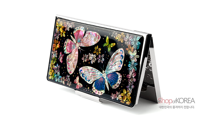 [텍스트: Shop of KOREA 대한민국의 품격까지 전합니다.] 흑색 바탕 위 천연 자개 상감 기법으로 표현된 다채로운 나비와 꽃문양이 어우러진 금속 명함케이스 이미지 설명