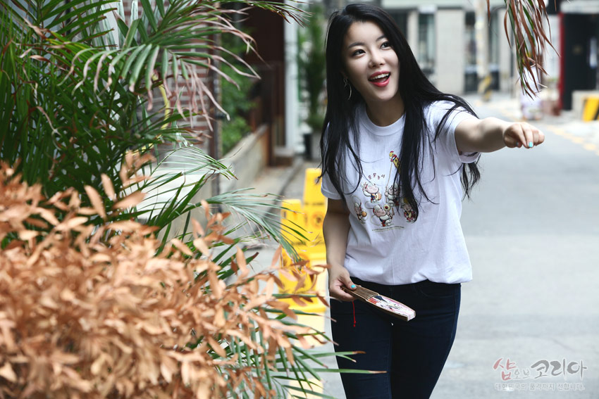 [텍스트: 샵오브코리아 / 아름다운 한국전통의 상품만을 선보입니다] 흰색 면 반팔에 풍물놀이 인물과 악기를 다색 3D 입체발포 기법으로 표현한 캐릭터 문양 티셔츠 모습