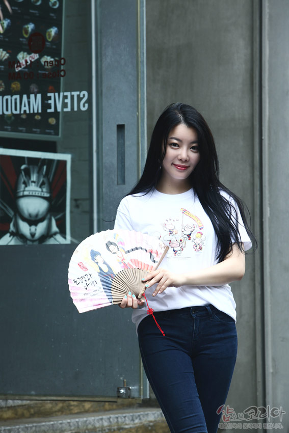 [텍스트: STEVE MADDEN] 흰색 순면 반팔에 다색 3D 입체발포 기법으로 표현한 풍물놀이 인물과 장단 문양, 밝은 색감의 캐릭터 일러스트가 돋보이는 디자인