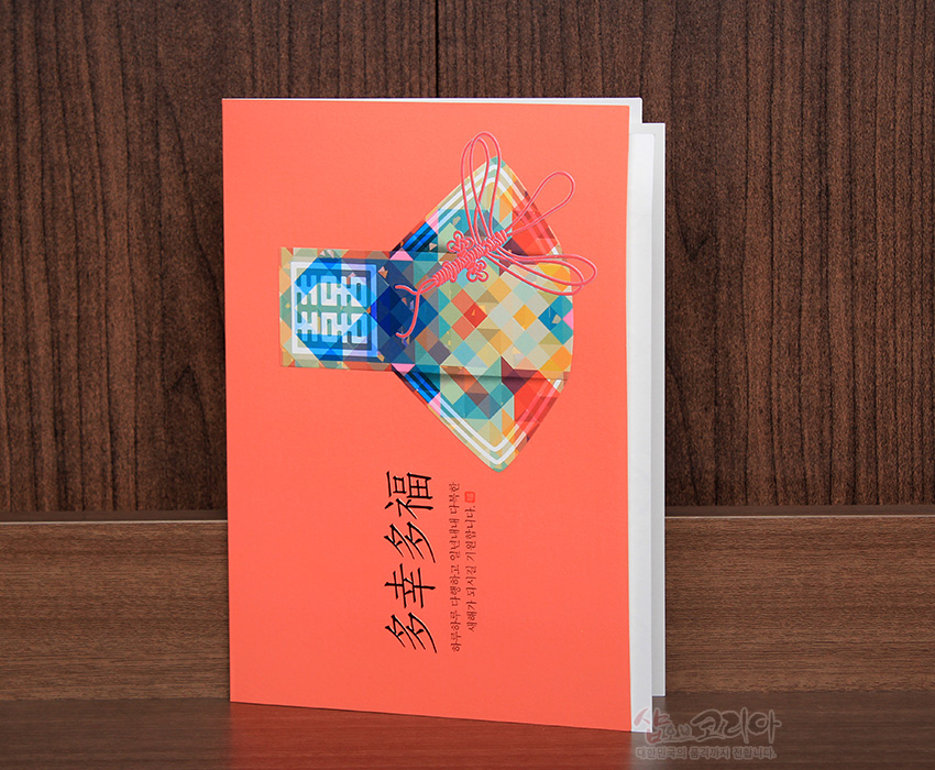 [텍스트: 多幸多福] 다채로운 색상의 체크 패턴 복주머니와 분홍 전통 매듭 장식이 인쇄된 주황색 배경 연하장 디자인