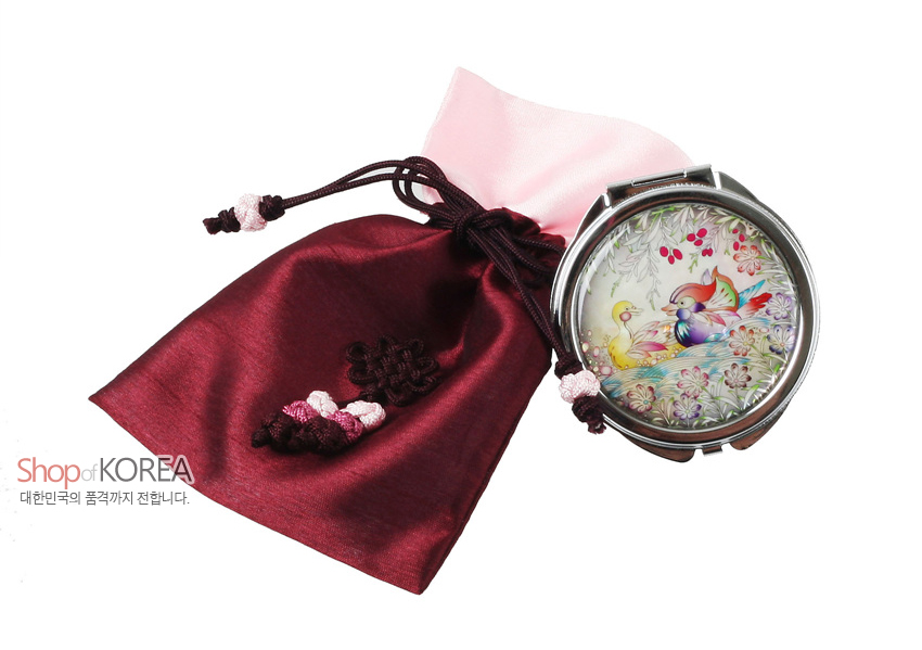 [텍스트: Shop of KOREA / 대한민국의 품격까지 전합니다.] 자개 상감 기법의 원앙·꽃문양 금속 손거울과 매듭 장식 자주색 비단 복주머니 세트 이미지 설명