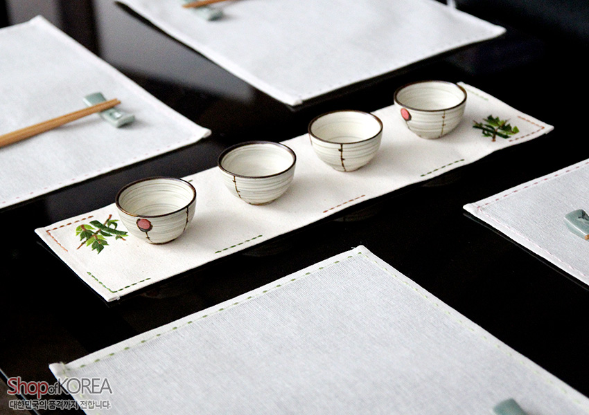 [텍스트: Shop of KOREA 대한민국의 품격까지 전합니다] 광목 재질 직사각 식탁 러너형 식탁보, 가장자리 컬러 스티치와 양 끝 매화·대나무 자수 장식 구성